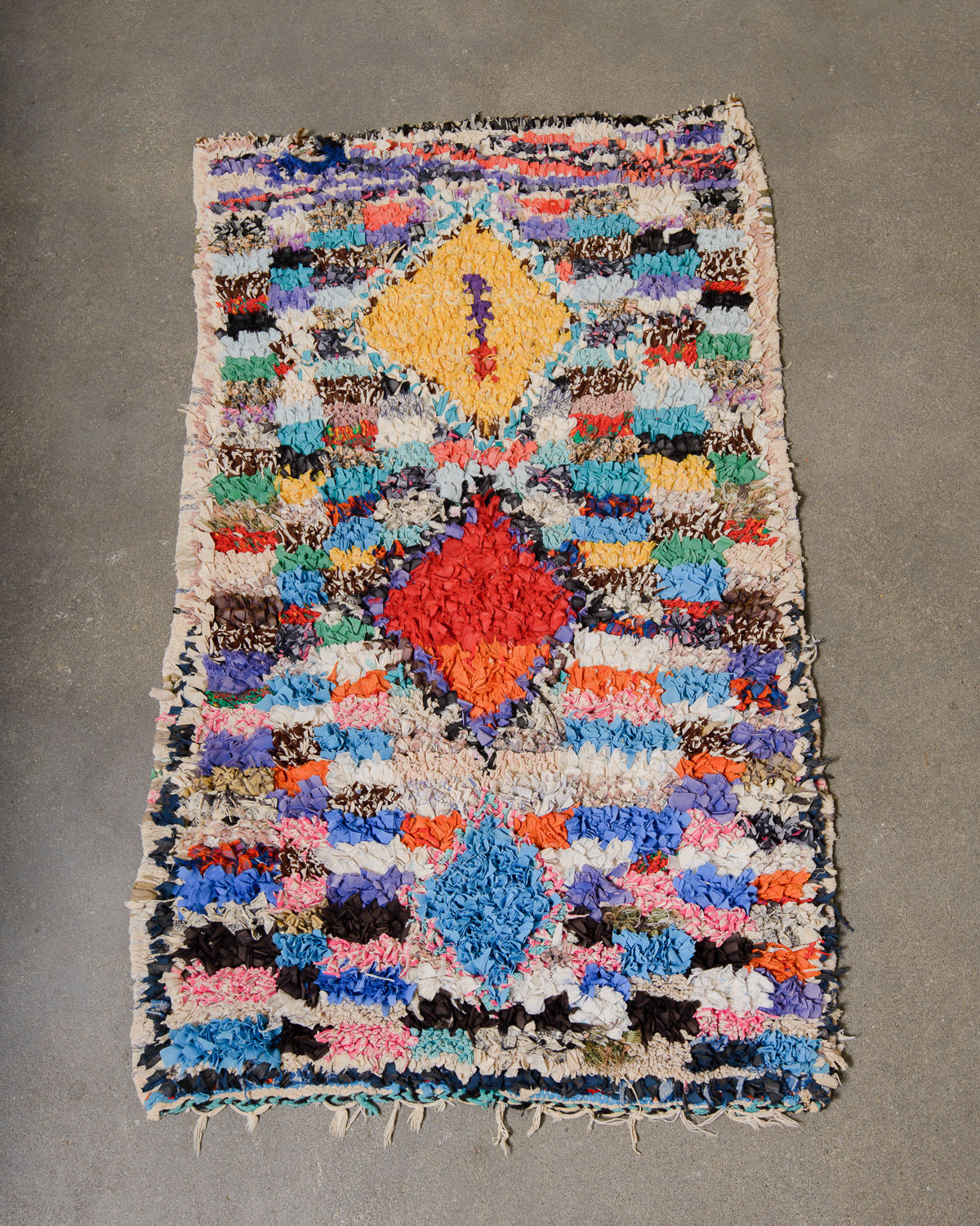 Berberlin vintage Boucherouite runner rug laying flat on concrete floor.
